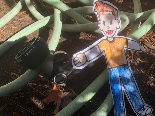 Flat Stanley hiding by the garden hose
